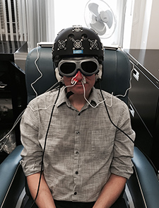 A staffer in Dr. Margaret Naeser's lab demonstrates the equipment built especially for the research: an LED helmet (Photomedex), intranasal diodes (Vielight), and LED cluster heads placed on the ears  