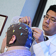 Dr. K. Luan Phan adjusts a volunteer's electrode cap. The researcher is studying the brain's 