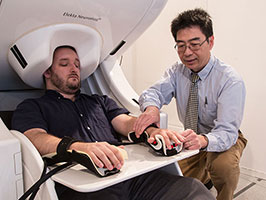 Dr. Mingxiong Huang prepares to do a MEG brain scan on a 