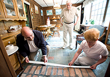  In this 2009 photo, caregiver Ann Cameron helps Scott Trudeau apply tape to a step in the home she shared with her husband, Donald (in the background), who has Alzheimer's disease. To prevent accidents on the stairs, highlight step edges with contrasting tape to make steps more visible. Two-inch duct tape works well. Put one strip across the entire edge of each step, with an inch covering the stair tread and an inch folded down below the edge of the step.