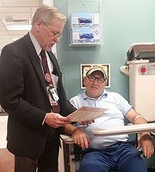  Dr. John Callaghan chats with Army Veteran Robert Knight, who served 25 years in the 82<sup>nd</sup> Airborne Division, as Knight prepares to provide a blood sample as part of his enrollment in VA's Million Veteran Program.
