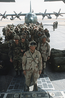 Army troops wait to board a C-130 for the trip to Fort Bragg, N.C., following the liberation of Kuwait during Operation Desert Storm. Behind the troops is another C-130 Hercules aircraft.s