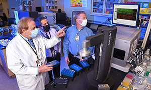 Dr. Steven A. Schichman, director of the Pharmacogenomics Analysis Laboratory at the Central Arkansas Veterans Healthcare System, demonstrates operation of a high-precision microarray scanner that supports precision medicine research. (From left to right: Dr. Schichman, Dr. Richard Owen, and Dr. Richard Dennis.)