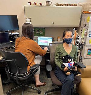Research coordinator Kim Schaper holds a tactile unit and controller—both are feedback mechanisms—while Dr. Caitlin Tyrrell monitors real-time brain activity. Based on the participant's feedback, the neurofeedback specialist adjusts frequency to locate the optimal setting.  